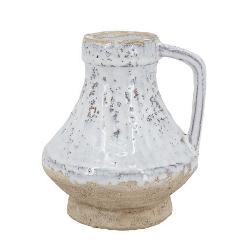 Small ceramic jug with single handle, wide squat body, mottled white-grey speckled glaze on upper half and raw sandy terracotta unglazed base, photographed on white background