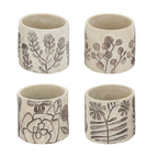 Set of four small cream ceramic pots each with a different hand-etched botanical design — fern sprig, eucalyptus branch, poppy with bee, and wildflower with fern — in stone-cream matte ceramic with brown etching, photographed on white background