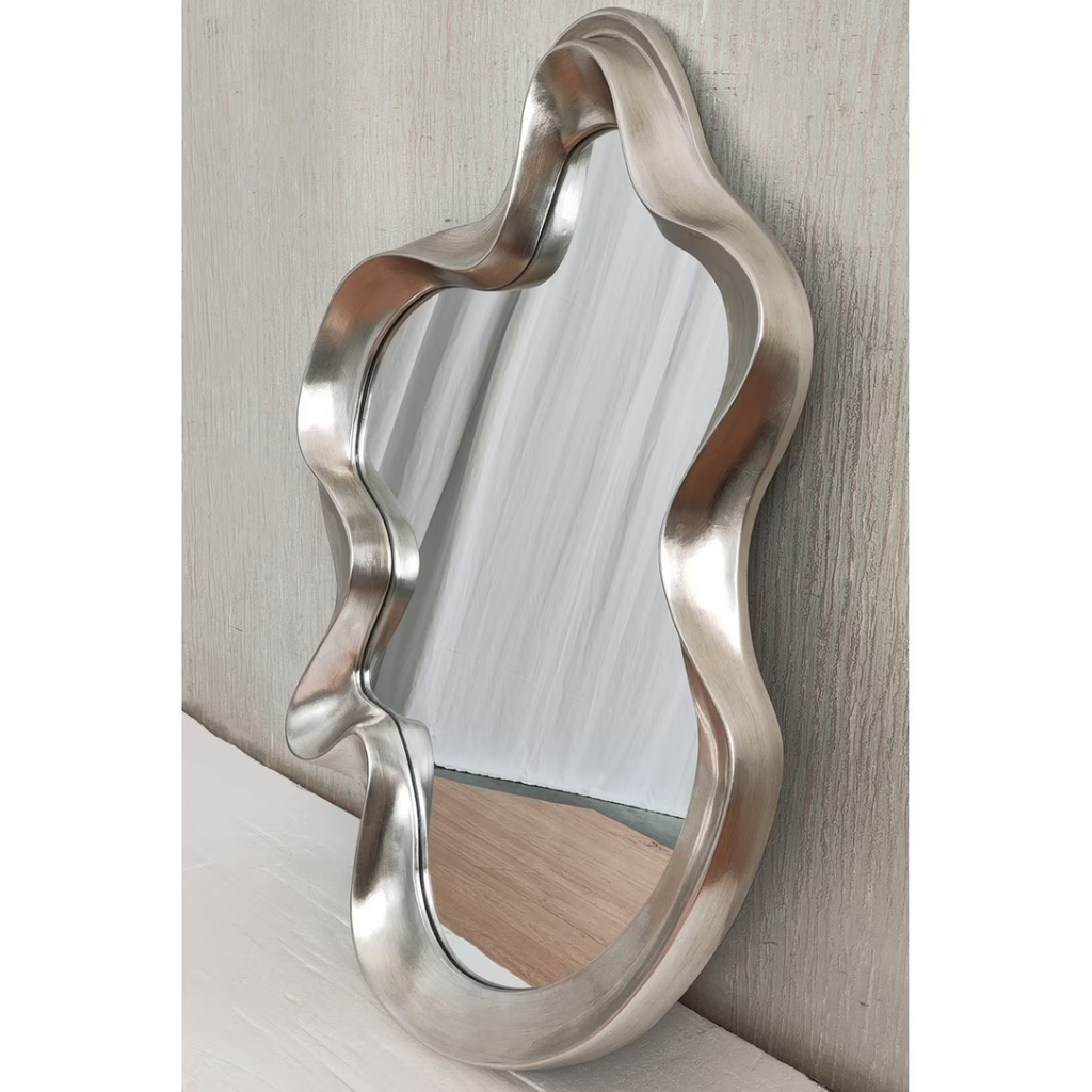 Large silver organic wavy mirror leaning against textured wall — Mish Lifestyle NZ