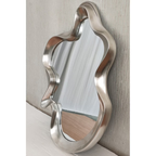 Large silver organic wavy mirror leaning against textured wall — Mish Lifestyle NZ