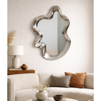 Silver sculptural wavy mirror hung above sofa in neutral living room styled with timber console and earthy cushions — Mish Lifestyle NZ