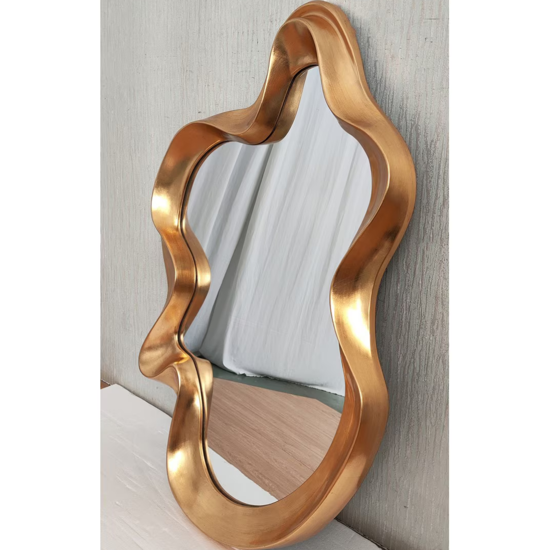 Large gold organic wavy mirror leaning against textured wall — Mish Lifestyle NZ
