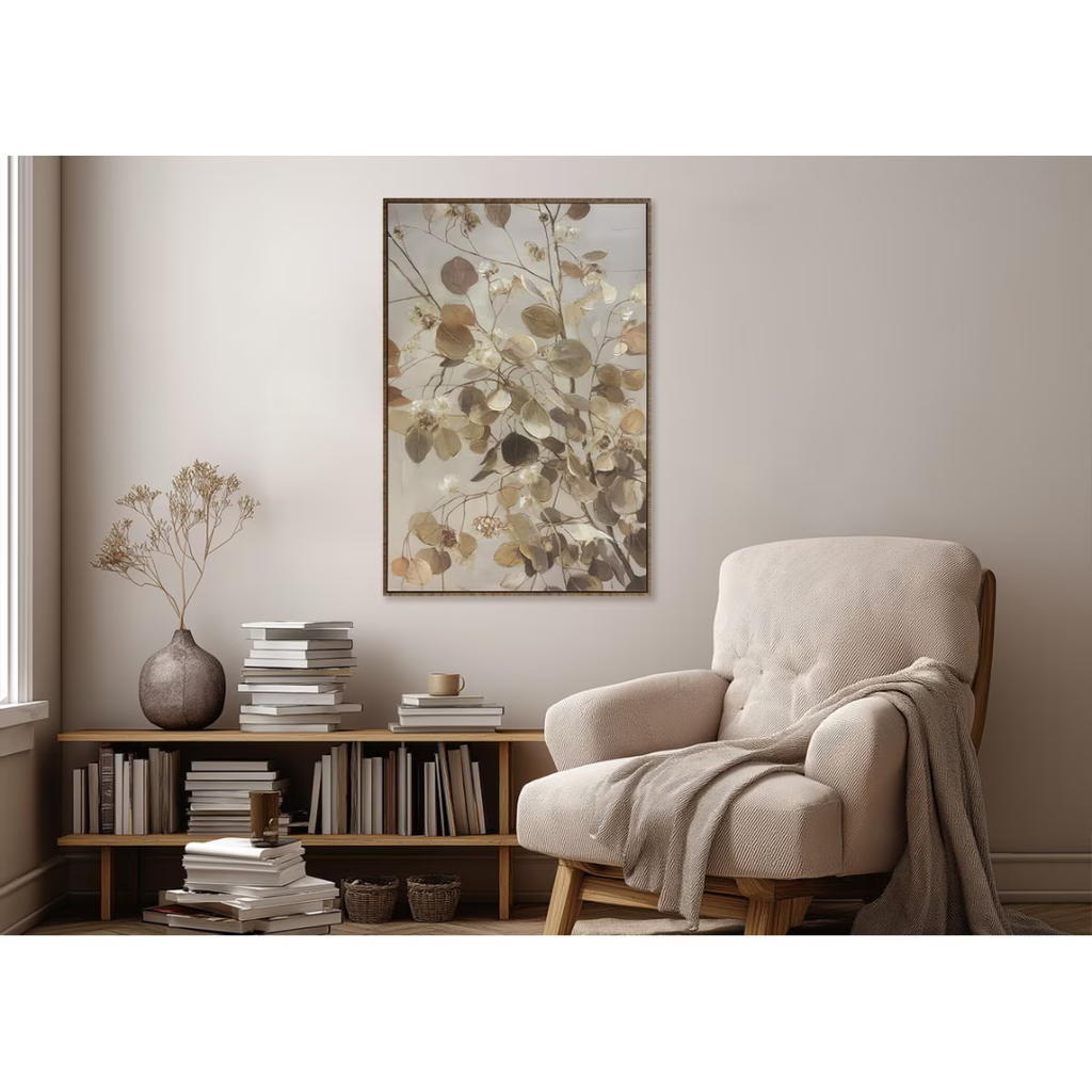 Beige armchair in a room with a bookshelf and floral artwork on the wall.
